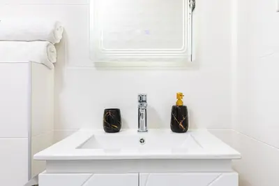 a white bathroom sink with two black bottles on it at Bright Windowed Studio 10 mins to the City Centre by Flat Mаnager in Plovdiv