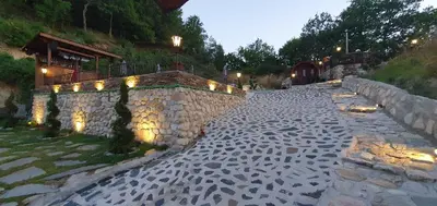 a stone path next to a stone wall with lights at Melnik Pyramids Guesthouse in Zlatkov Chiflik