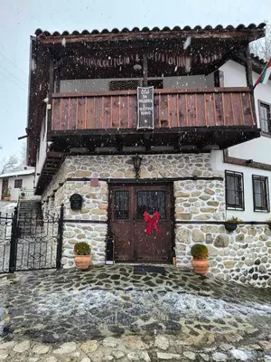 a stone building with a door with a red bow on it at Melnik Pyramids Guesthouse in Zlatkov Chiflik