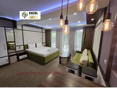 a bedroom with a bed and a couch and a table at Уютная студия Green Life E 04 in Bansko