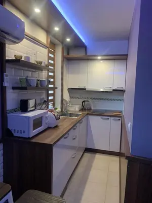 a kitchen with white cabinets and a microwave on a counter at Уютная студия Green Life E 04 in Bansko