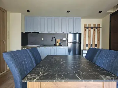 a kitchen with a black marble table and blue chairs at CROWN Apartment Bansko in Bansko