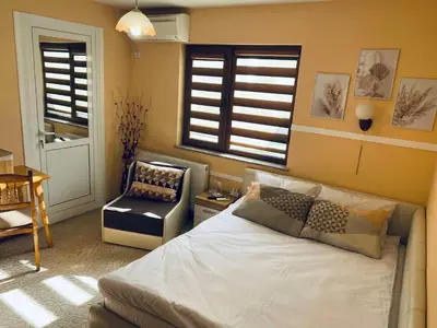 a bedroom with a bed and a chair and windows at Къща за гости Василеви in Bratsigovo