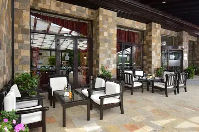 a patio with chairs and tables and windows at Pamporovo hotel Snezhanka A640 in Pamporovo