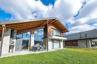 a house with glass windows and a lawn at Lavalliere Hotel & Villas in Sarnitsa