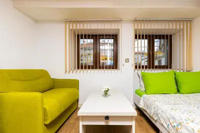a living room with a yellow couch and a bed at Tiny Secret Place next to MU with Private Parking in Plovdiv