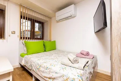 a bedroom with a bed with green pillows and a tv at Tiny Secret Place next to MU with Private Parking in Plovdiv