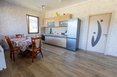 a kitchen with a table with chairs and a refrigerator at Къща за гости Дар in Batak