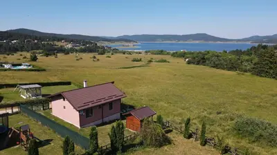 a house in a field next to a lake at Къща за гости Дар in Batak