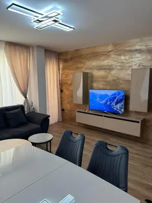 a living room with a television and a table and chairs at Патилови in Sandanski