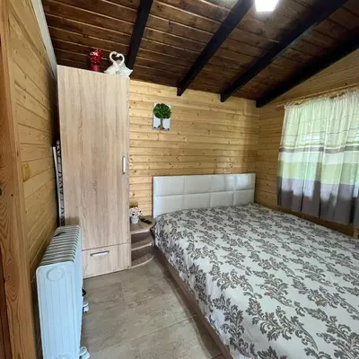a bedroom with a bed in a wooden cabin at Вила Сънсет 1 in Dospat