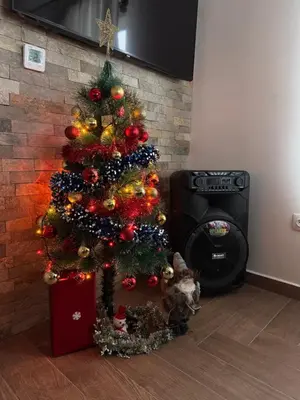 a christmas tree in a room next to a fireplace at Вила Сънсет 2 in Dospat