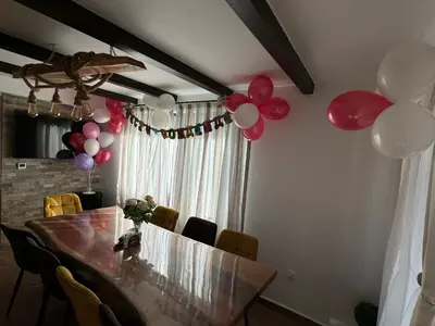 a dining room with a table with balloons on the wall at Вила Сънсет 2 in Dospat