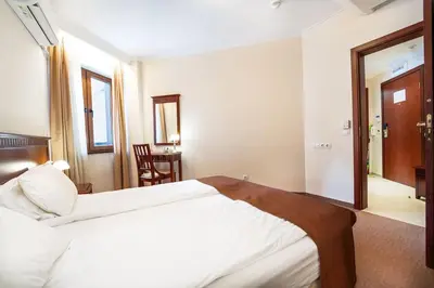 a hotel room with a large bed and a table at Host2U Slope-Side Home by the Gondola in Bansko