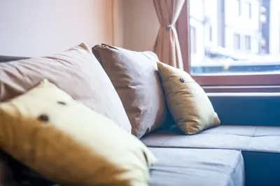 a group of pillows on a couch with a window at Host2U Slope-Side Home by the Gondola in Bansko