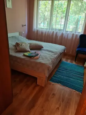a bedroom with a bed with a blue rug and a window at South Park apartment free parking near Tokuda in Sofia