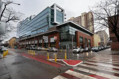 a city street with cars parked in front of a building at Megan apartment Sofia Mall center in Sofia