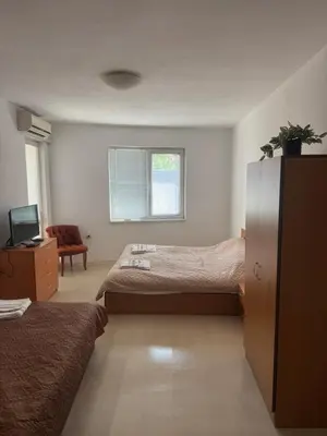 a bedroom with two beds and a chair and a window at Апартамент за гости ''ЗДРАВЕ'' in Kyustendil
