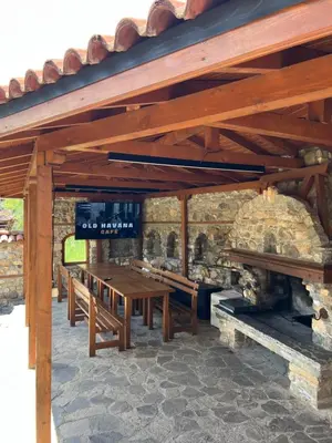a group of wooden tables and benches under a stone building at Villa Martina in Smilyan
