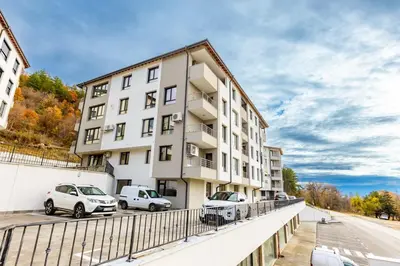 an apartment building with cars parked in a parking lot at Apartment Golden Park in Sandanski