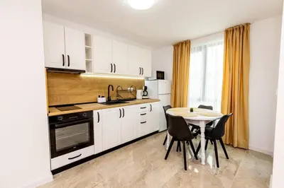 a kitchen with white cabinets and a table with chairs at Apartment Golden Park in Sandanski
