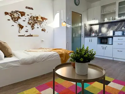 a room with a bed and a table and a kitchen at Comfy Studio by Cosher in Sofia