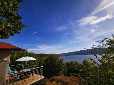 a deck with an umbrella and a view of a lake at Lakeview Estate Chalet in Staro Myasto