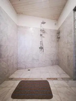 a bathroom with a shower with a rug on the floor at Lakeview Estate Chalet in Staro Myasto