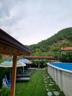 a pool with chairs and umbrellas next to at Villa Popovi in Simitli