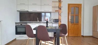 a kitchen with a table with chairs and a bottle of wine at Студио Вили in Smolyan