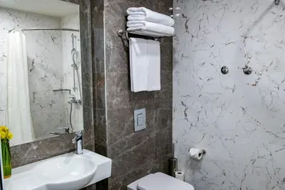 a bathroom with a sink and a toilet and a mirror at BG Hotel in Sofia