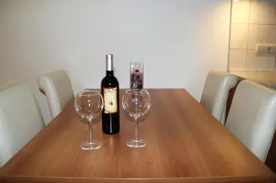 a bottle of wine and two wine glasses on a wooden table at Prime location one bed apartment with hydro bath in Royal Plaza in Borovets