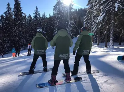 a group of people standing on snowboards in the snow at Prime location one bed apartment with hydro bath in Royal Plaza in Borovets