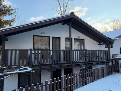 a white house with a wooden balcony at Къща за Гости БАРБЕЛ in Golyam Izvor