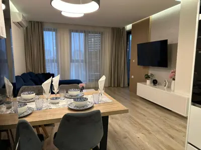 a living room with a table with chairs and a television at Delux 1 - Plovdiv Луксозен апартамент с паркинг in Plovdiv