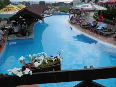 a large swimming pool with people sitting on chairs in a resort at Elegant Apartment Ski Access Premium Spa in Bansko