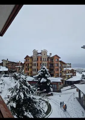 a group of people walking down a street in the snow at Pirin Golf Hotel & Spa in Razlog