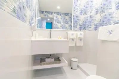 a white bathroom with a sink and a mirror at Lambrina Boutique rooms in Plovdiv