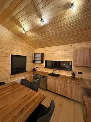a kitchen with wooden walls and a table and a television at Stylish Alpine Ski Chalet Tirol in Borovets