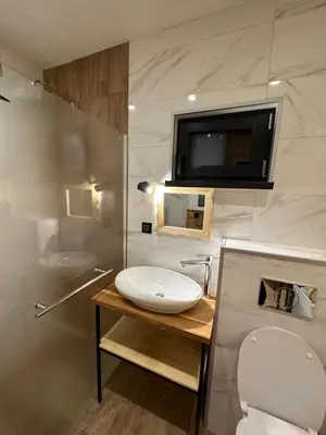 a bathroom with a sink and a tv on the wall at Stylish Alpine Ski Chalet Tirol in Borovets