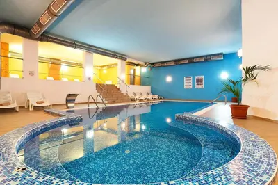 a large swimming pool with blue tiles in a building at Alenik Private Apartment -The Stream Resort Pamporovo in Pamporovo