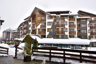 a snow covered building with a fence in front of it at Exclusive Ski and Spa Paradise Stylish Apartment in Bansko