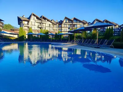 a large swimming pool with blue umbrellas and chairs at Aspen Resort Studio I306 in Razlog