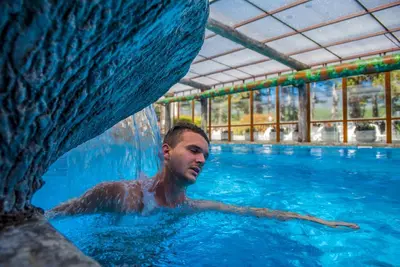 a man is swimming in a swimming pool at SPA Hotel Elbrus in Velingrad