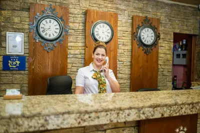a woman talking on a cell phone behind a counter with clocks at SPA Hotel Elbrus in Velingrad