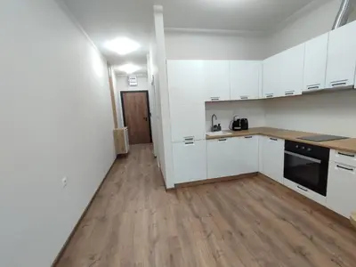 a kitchen with white cabinets and a wooden floor at Pana Green Residence in Panagyurishte