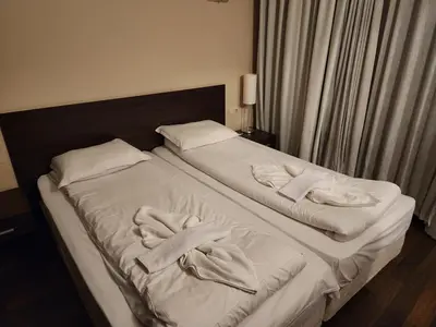 a bed with white sheets and towels on it at Pirin View Apartment in Bansko