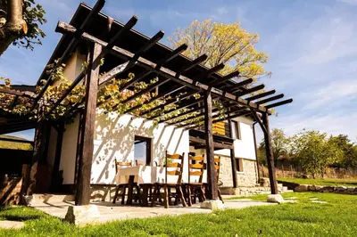 a wooden pergola with a table and chairs under it at Гусу Баба in Kostenets Village