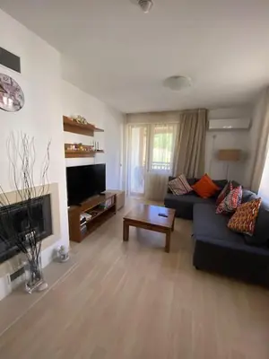a living room with a couch and a tv at St John Hill Alexander Services Apartments in Bansko