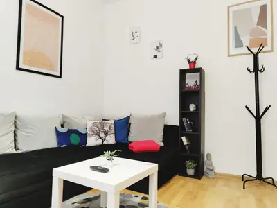 a living room with a black couch and a white table at Apartment for four next to blvd Vitosha in Sofia